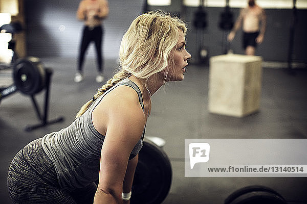 Side view of determined female athlete exercising in gym