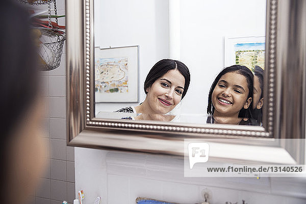 Reflection of mother and daughter in bathroom mirror