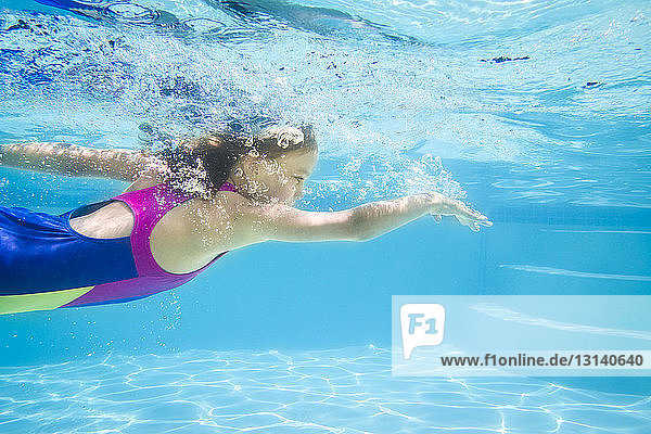 Side view of girl swimming underwater