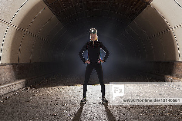 Porträt einer selbstbewussten Frau  die mit den Händen auf der Hüfte im Tunnel steht