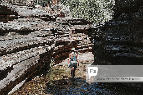 Rückansicht einer Frau  die im Fluss inmitten von Felsformationen im Grand Canyon National Park wandert