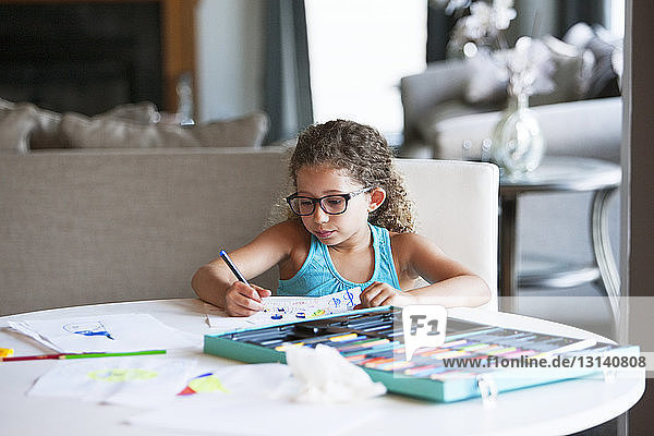 Girl coloring with felt tip pen on paper at table