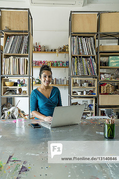 Porträt einer selbstbewussten Geschäftsfrau  die am Laptop im Büro arbeitet