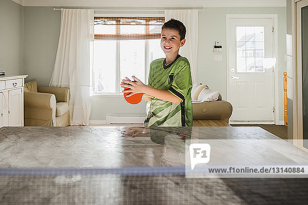 Glücklicher Junge spielt zu Hause Tischtennis