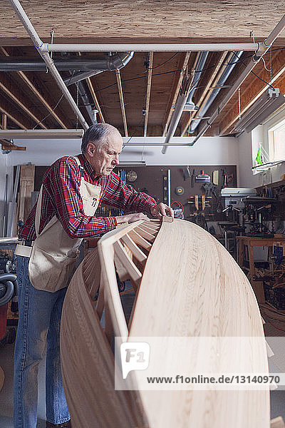 Älterer Mann arbeitet auf einem Holzboot in der Werkstatt