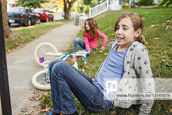 Schwestern mit Fahrrad auf Grasfeld sitzend