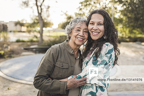 Porträt einer glücklichen Tochter  die eine ältere Mutter umarmt  während sie im Park steht