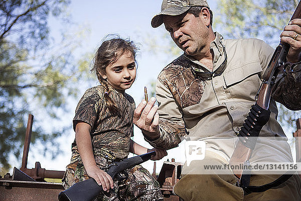 Mann erklärt seiner Tochter eine Kugel  während er auf einer Maschine sitzt
