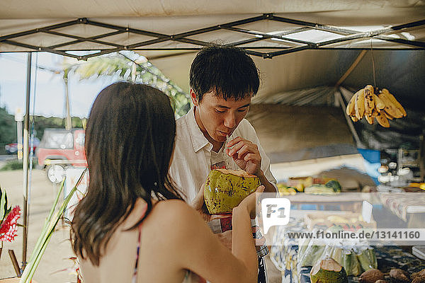 Ehepaar trinkt Kokosnusswasser am Marktstand