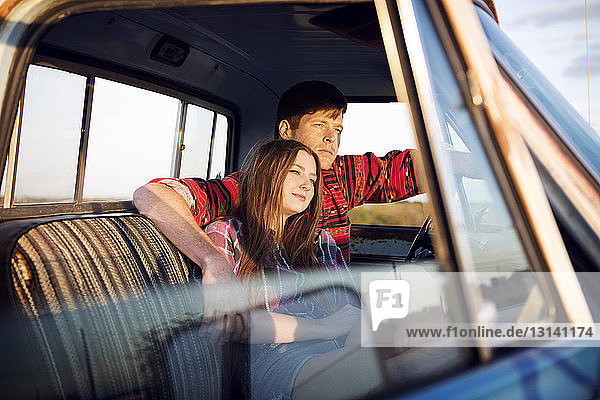 Couple sitting in pick-up truck during sunset