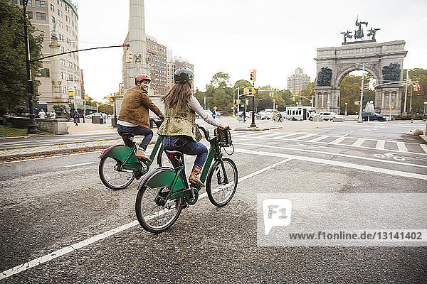 Couple riding bicycle on city street