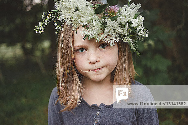 Close-up portrait of girl wearing flowers while standing at farm