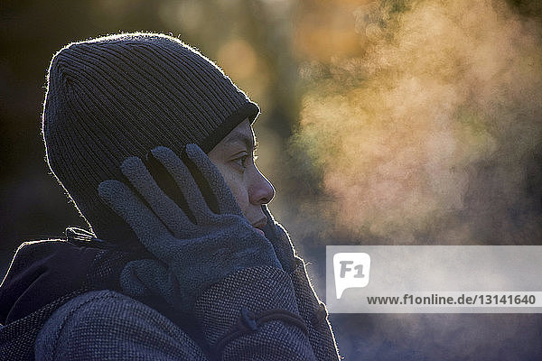 Nahaufnahme einer Frau  die im Winter im Park Atemdampf ausatmet