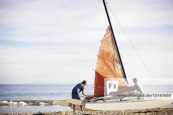 Familie baut Segelboot  während sie am Strand steht