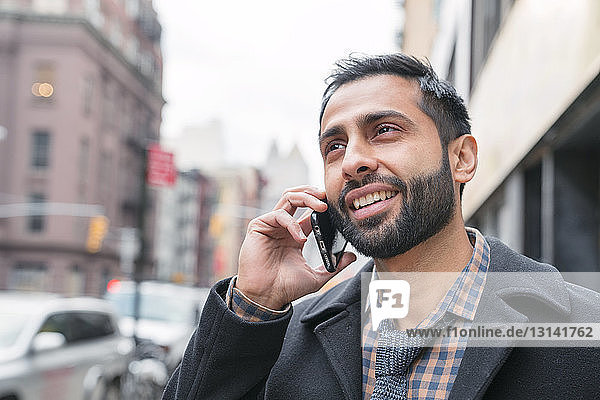 Geschäftsmann spricht mit einem Smartphone  während er in der Stadt steht