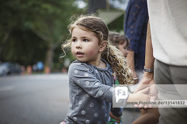 Mädchen schaut weg  während sie die Hand des Vaters auf der Straße hält