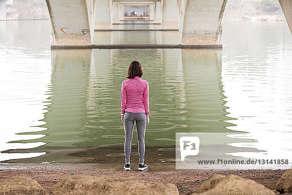 Rückansicht einer Frau  die am Seeufer unterhalb der Lamar-Boulevard-Brücke trainiert