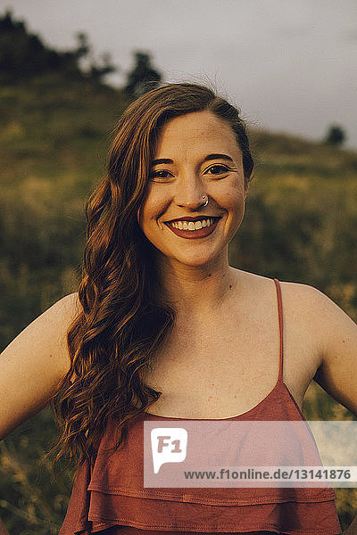 Portrait of cheerful young woman standing on field