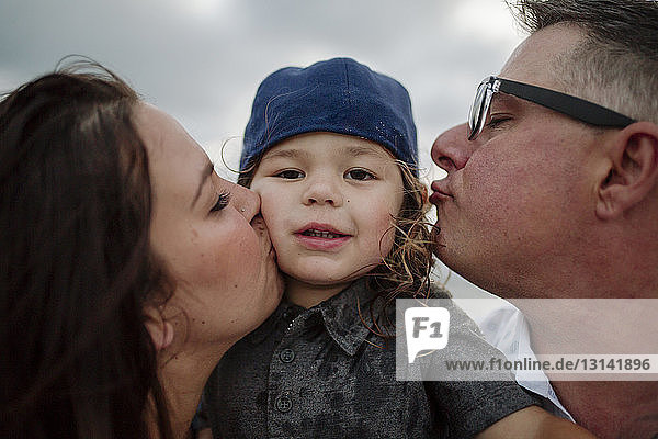 Porträt eines süßen Sohnes mit sich küssenden Eltern