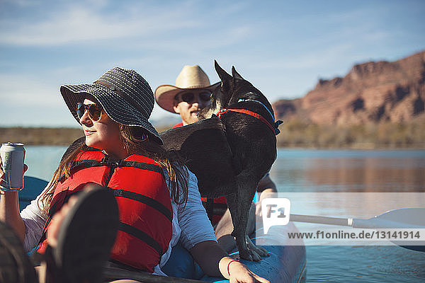 Friends with dog sitting in inflatable kayak on lake