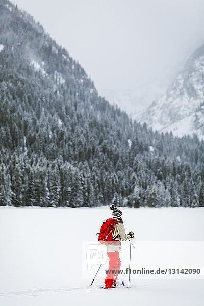 Frau mit Rucksack wandert auf schneebedecktem Feld