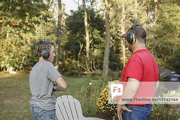 Son looking at father while holding rifle at backyard