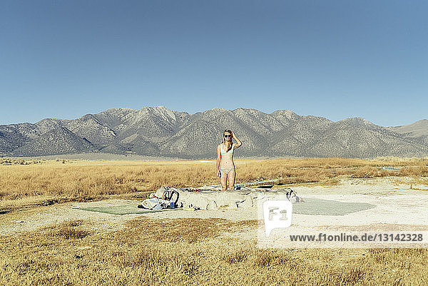 Woman in swimming pool on field by mountains against clear sky