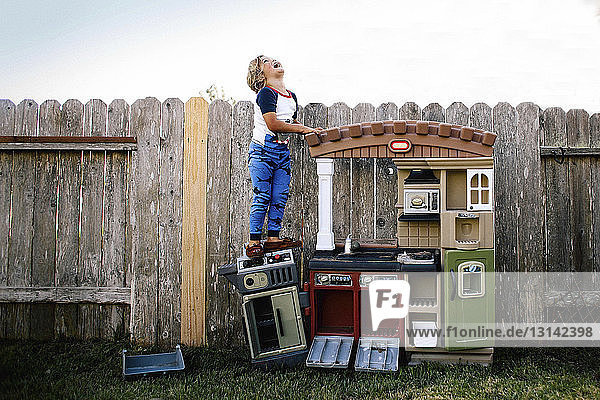 Fröhliches Mädchen steht auf Spielzeugküche im Hinterhof vor klarem Himmel