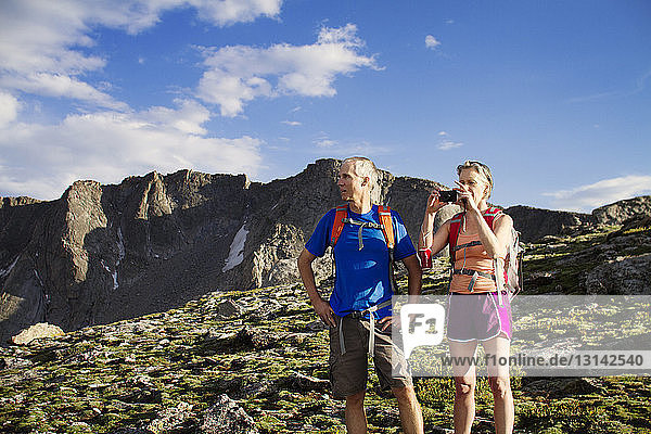 Woman photographing while man standing on mountain