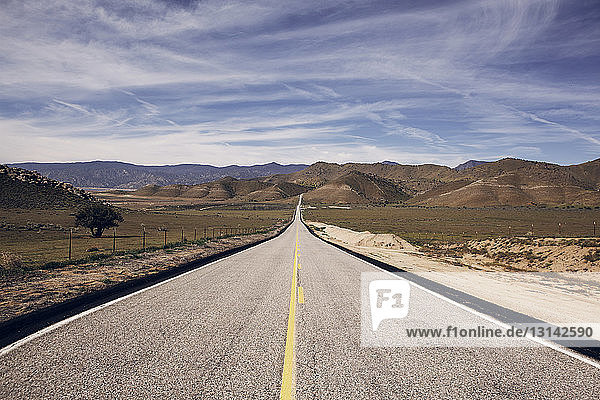 Landstraße führt zu den Bergen im Death Valley National Park gegen den Himmel