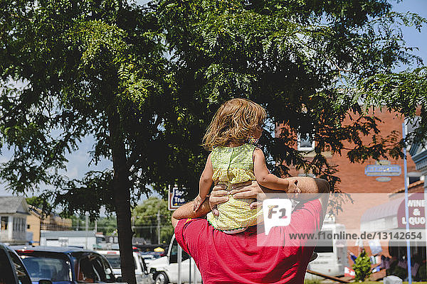 Rückansicht eines Mannes mit Tochter beim Spaziergang in der Stadt