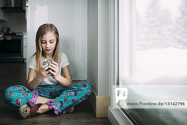 Mädchen in voller Länge benutzt zu Hause ein Mobiltelefon