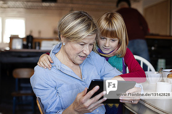 Großmutter und Enkelin schauen auf Tablet-Computer