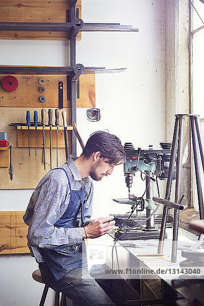 Male craftsperson working on machinery at wood shop