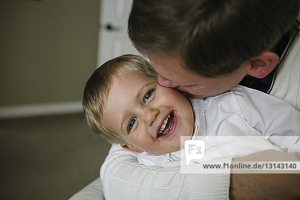 Glücklicher Vater küsst Sohn  während er zu Hause sitzt