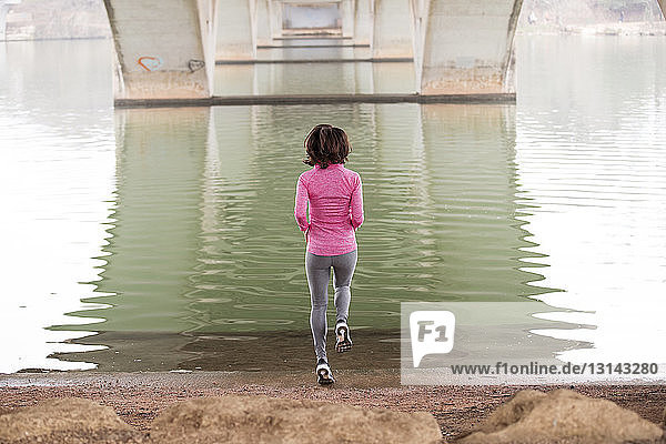 Rückansicht einer Frau  die am See unterhalb der Lamar-Boulevard-Brücke springt