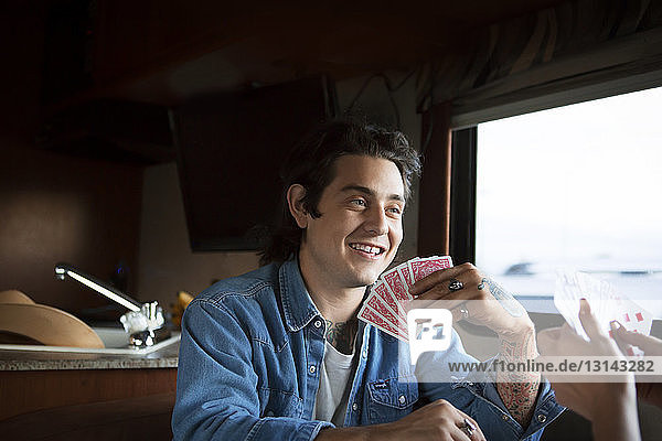 Glücklicher Mann spielt mit seiner Freundin Karten  während er im Wohnmobil sitzt