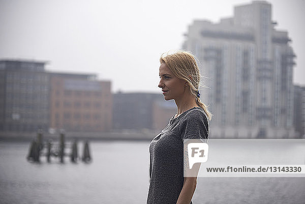 Seitenansicht einer nachdenklichen Geschäftsfrau  die weg schaut  während sie am Fluss in der Stadt steht