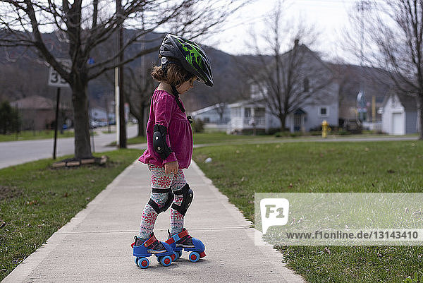Seitenansicht eines Mädchens beim Rollschuhlaufen auf einem Fußweg im Park