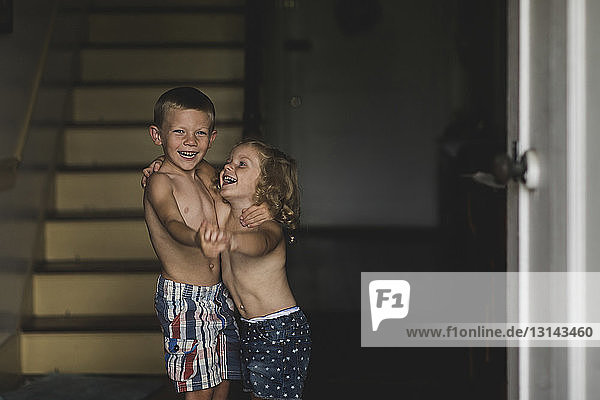 Happy shirtless siblings dancing at home