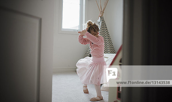 Girl in ballet costume dancing at home seen through doorway