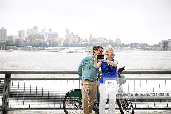 Fröhliches reifes Paar  das sich auf der Promenade am Fluss in der Stadt selbstständig macht