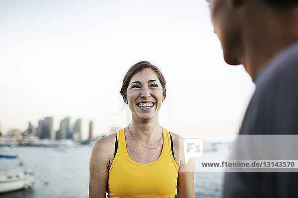 Happy female athlete talking to man by harbor