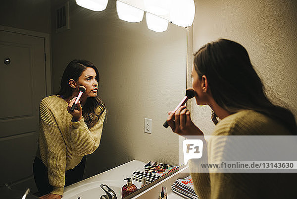 Frau trägt Make-up auf und reflektiert auf Spiegel