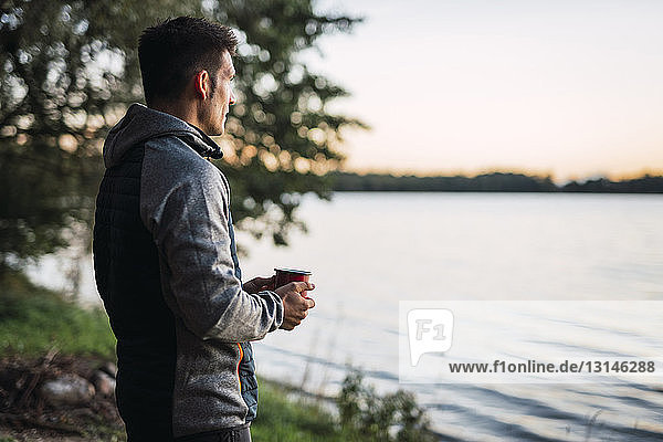 Man looking at the lake drinking coffee