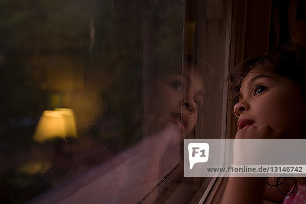 Young girl looking through window