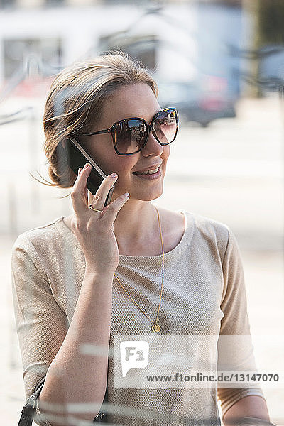 Young woman on mobile phone outside shop window