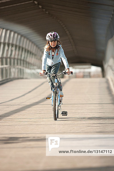 Girl riding bicycle in city tunnel