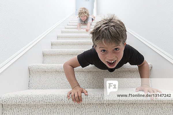 Porträt von zwei Brüdern  die kopfüber eine Treppe hinunterkriechen