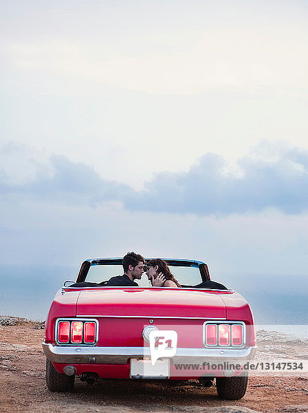 couple sitting in front of cabriolet